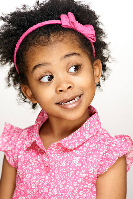 Child actor has mischevious look as she poses for headshot with studio lighting